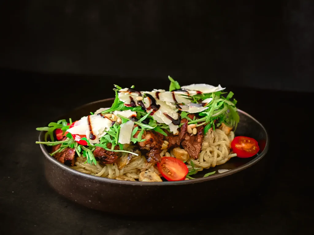 Runderribbeye geserveerd met romige pasta op basis van truffel. Afgewerkt met parmezaanse kaas.