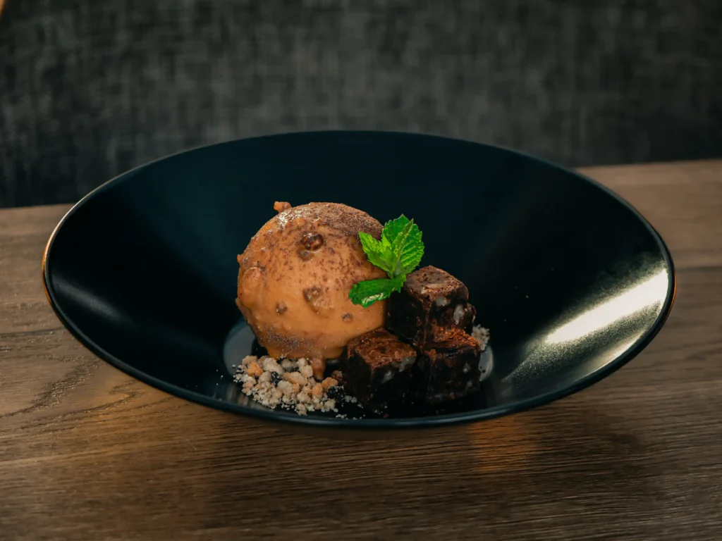 Tiramisuroomijs met chocoladecake en een vleugje amaretto-koffie. Geserveerd met stukjes brownie & cookie crumble.