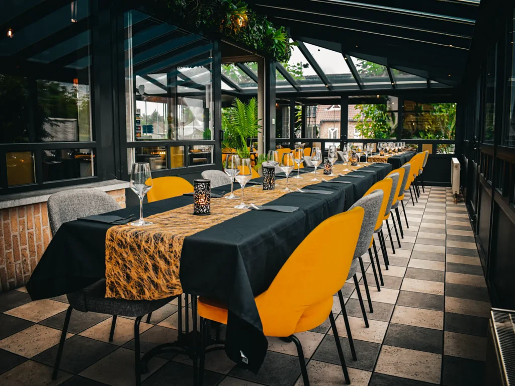 Veranda met lange tafels bij Happy Days, ideaal voor een feestje of als restaurant voor grote groepen. Brasserie Happy Days in Pelt