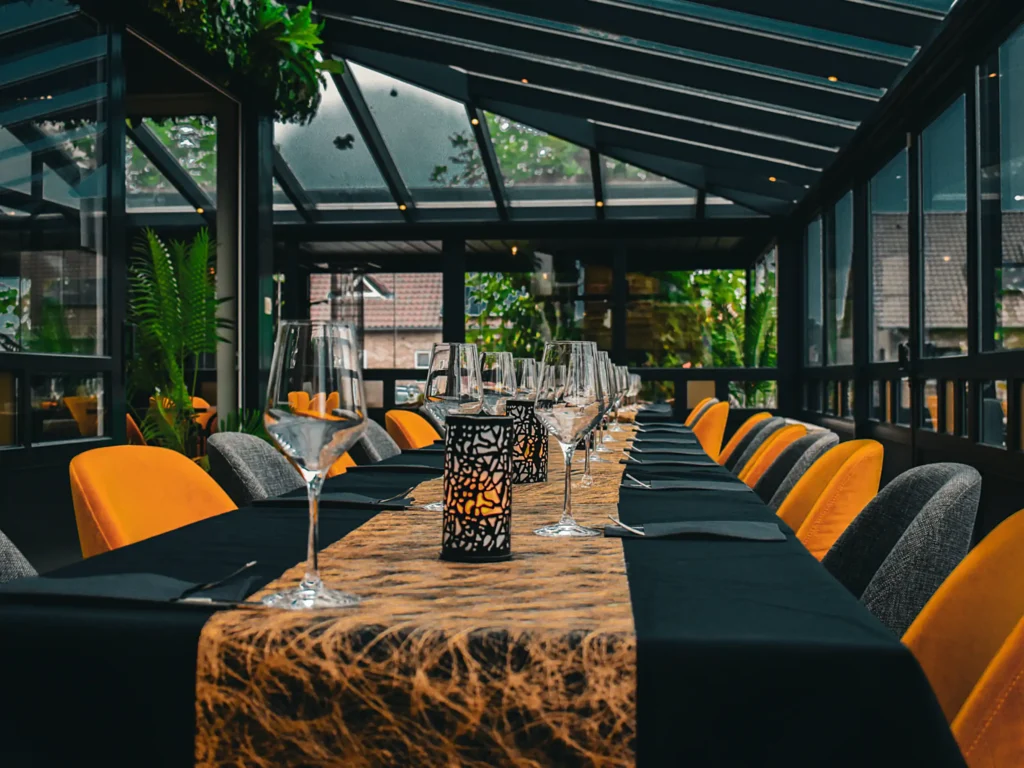 Veranda met lange tafels bij Happy Days, ideaal voor een feestje of als restaurant voor grote groepen. Brasserie Happy Days in Pelt